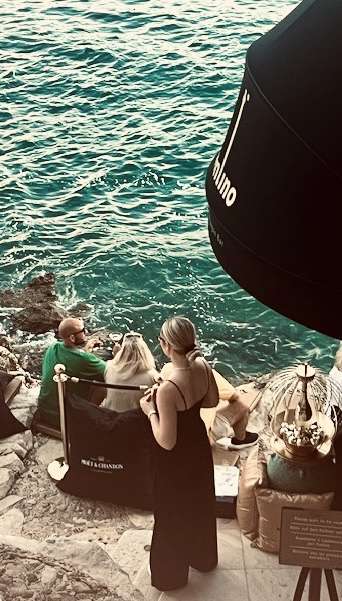 Four young people sitting on the rocks at cocktail hour in Rovinj, Croatia